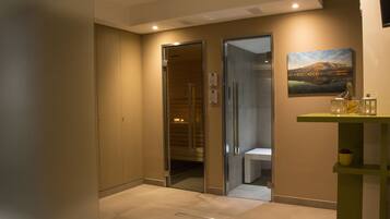 A hotel lobby with a reception desk, a painting on the wall, and a glass elevator.