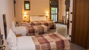 A hotel room with two beds, a wooden door, and a window with a view of trees. - Hotel Parini (Bosisio Parini)