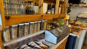 Zona de bufé con diversos alimentos, incluyendo pasteles y frutas, así como una selección de bebidas.