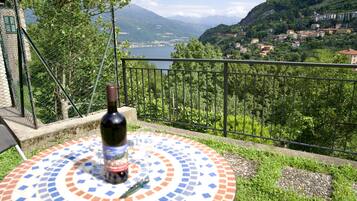 Ein Tisch mit einer Weinflasche und einem Glas, mit Blick auf einen malerischen See und eine gebirgige Landschaft.