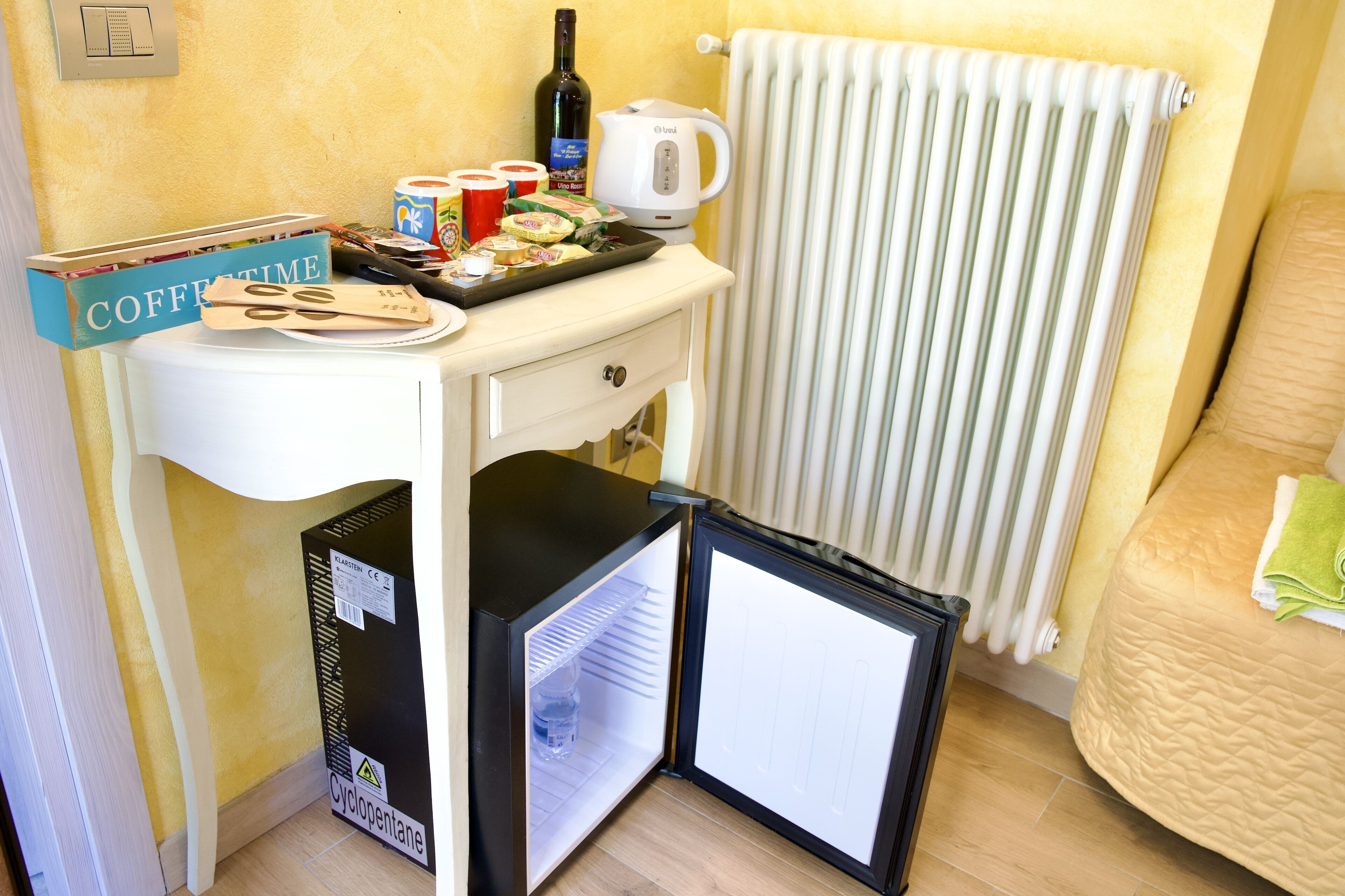 A compact kitchenette with a refrigerator, a coffee maker, and a small countertop with food items.