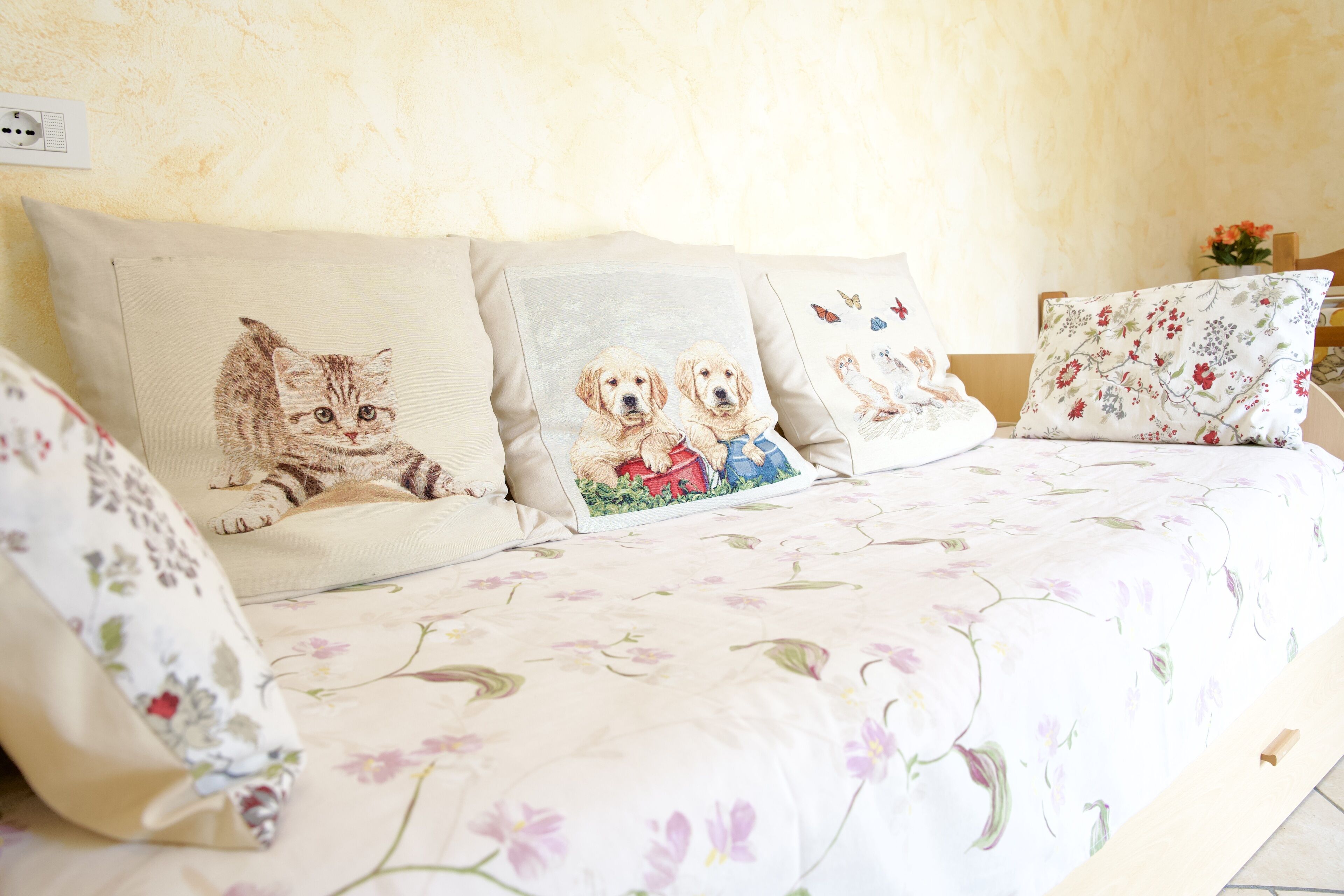 A bed with floral bedding and pillows featuring animal prints.