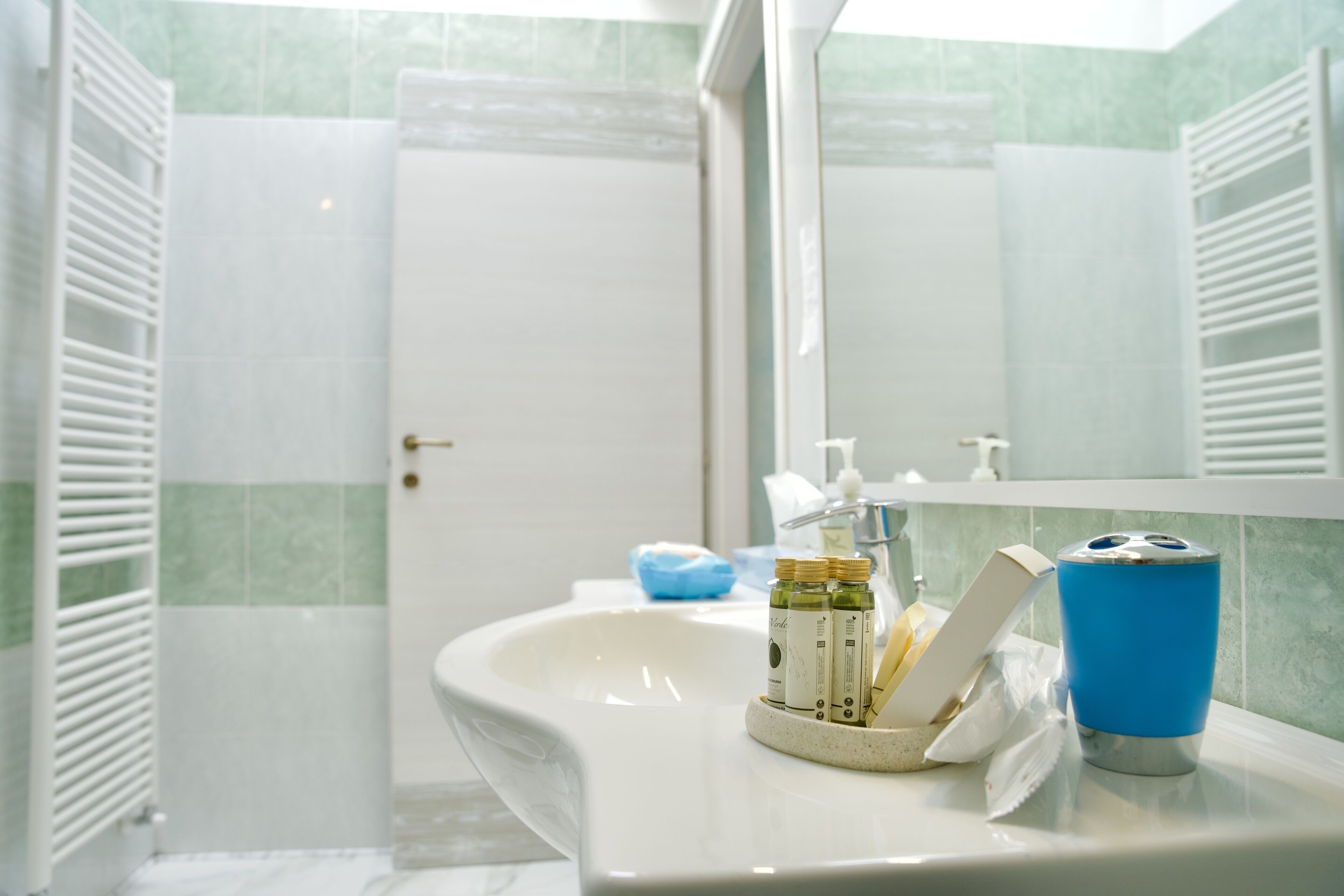 A bathroom with a white sink, a mirror, and toiletries.