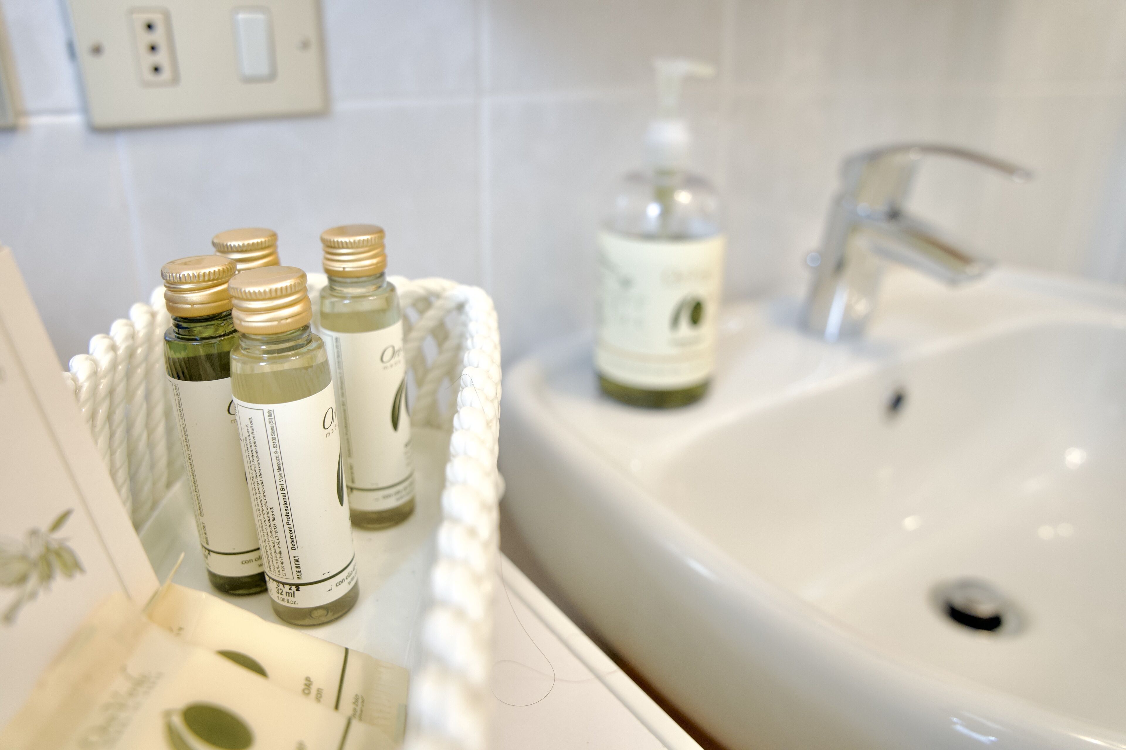 A bathroom sink with a bottle of hand soap and a bottle of lotion.