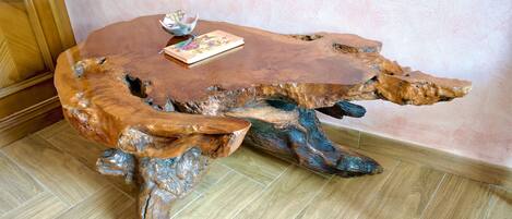 A uniquely shaped wooden table with a book and a small bowl on top.