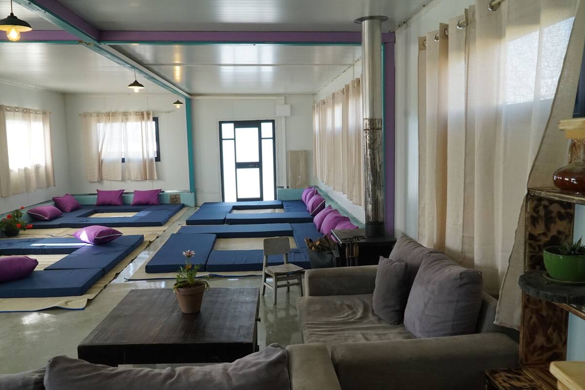 Ein Yoga-Studio mit mehreren in Reihen angeordneten Matten, einer Holzbank und einem Sofa.