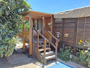 Une cabane en bois dotée d’un porche couvert et d’un escalier menant à une terrasse.