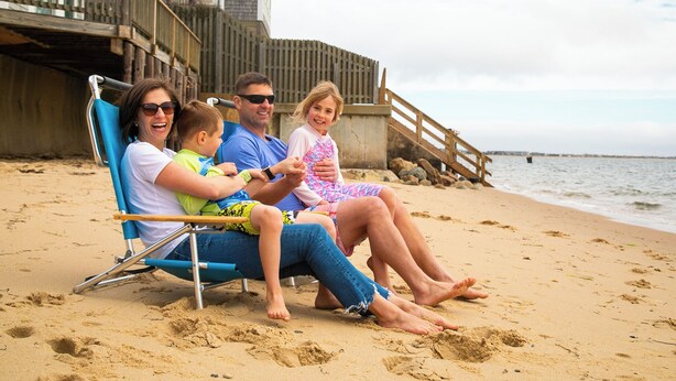 A family on a sandy beach with a wooden deck and a wooden railing in the background. - Cape Colony Inn (Provincetown)