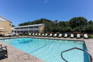 En swimmingpool med solstolar och en byggnad i bakgrunden.