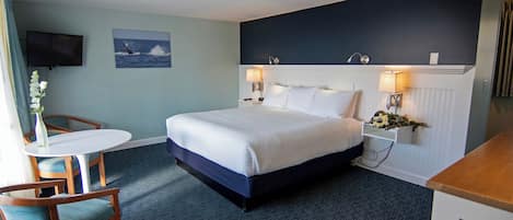 A bedroom with a bed, bedside tables, a TV, and a window with curtains.