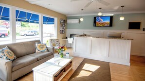 A living room with a sofa, coffee table, and a TV mounted on the wall. - Cape Colony Inn (Provincetown)