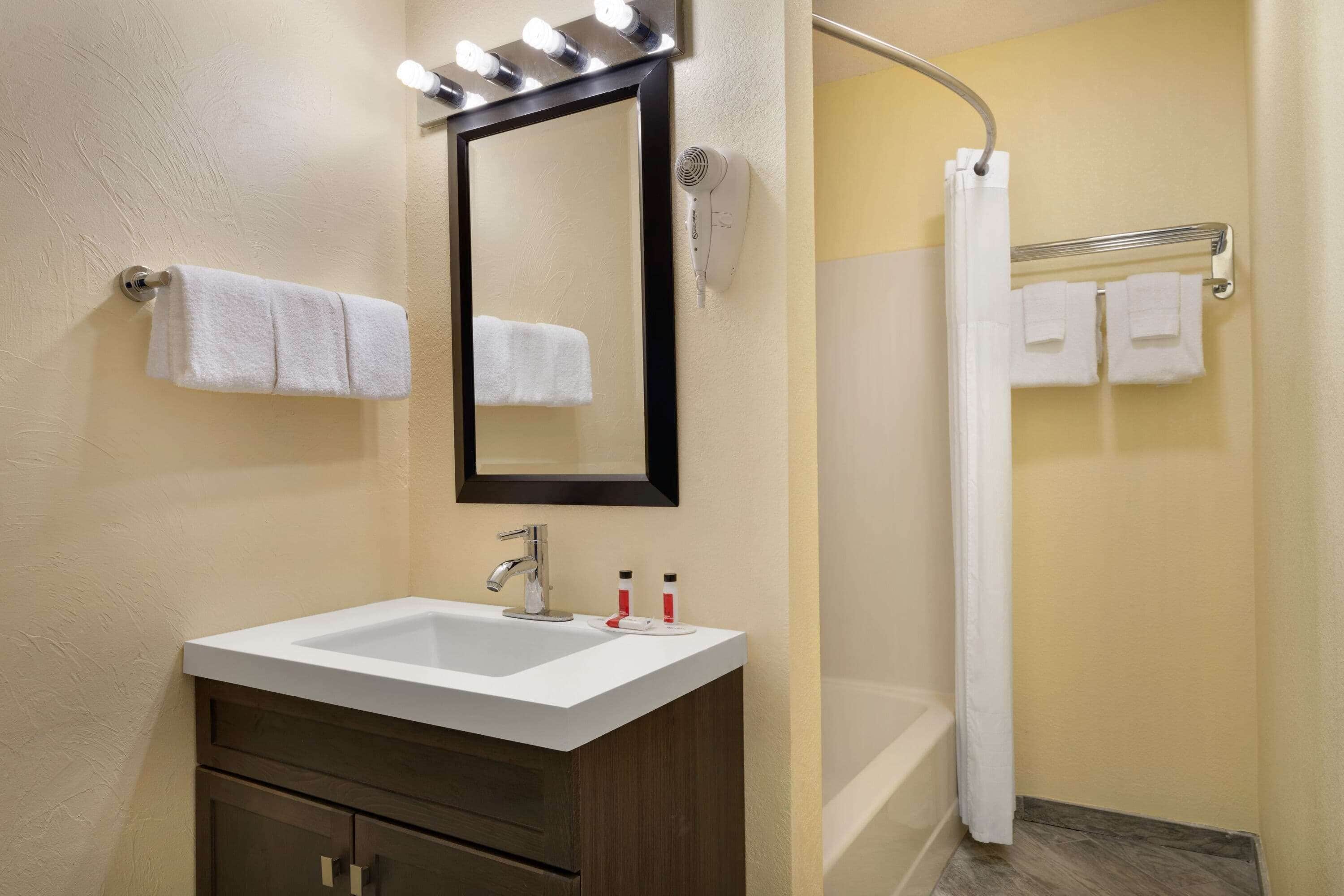 Un baño con lavabo, espejo y perchero para toallas.
