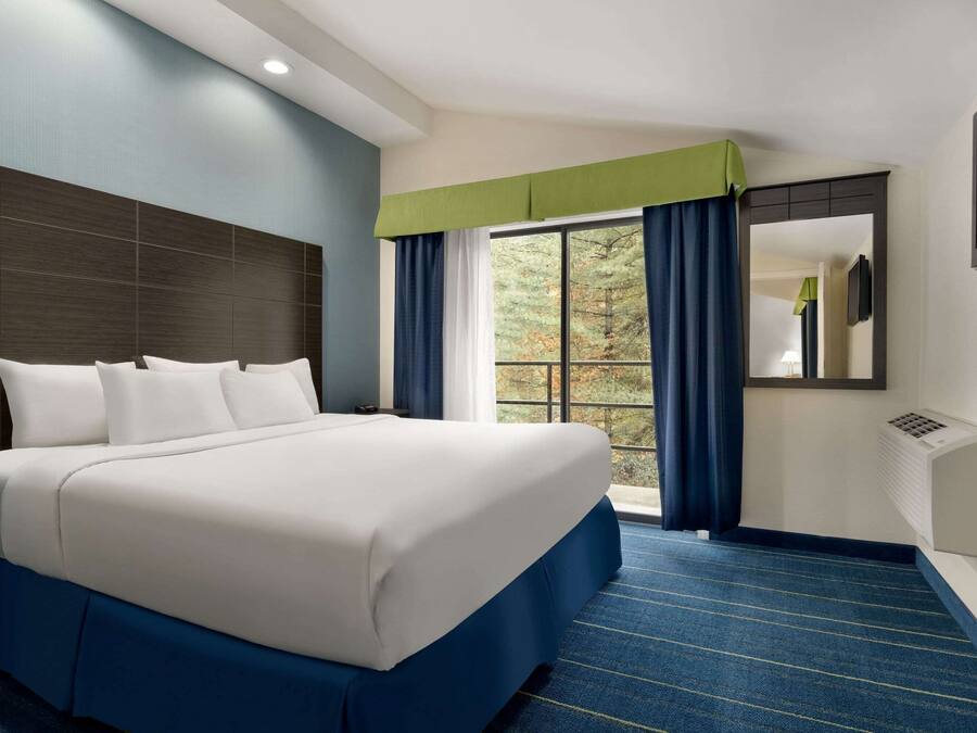 Habitación de hotel con una cama grande, una ventana con cortinas, un televisor de pantalla plana y un aire acondicionado de pared.