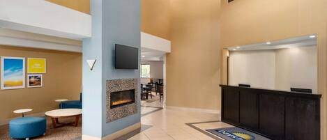 Un vestíbulo moderno con chimenea, zona de estar y mostrador de recepción.