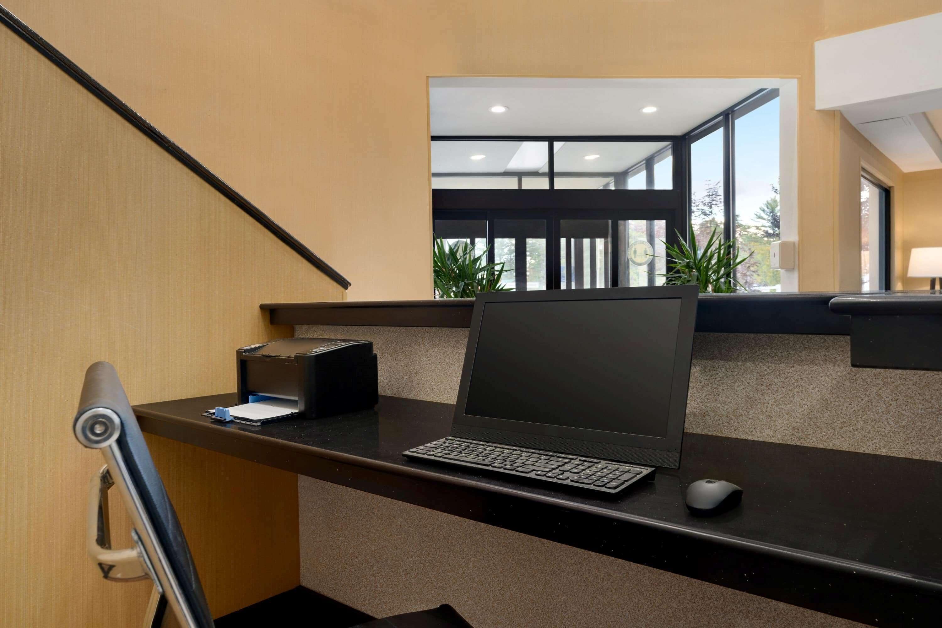 Een modern bureau met een laptop, toetsenbord, muis en een printer.