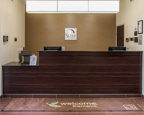 A reception desk with a sign reading "Sleep Inn & Suites" and a welcome mat with "Welcome Bismarck" text. - Sleep Inn & Suites Bismarck I-94 (Bismarck)
