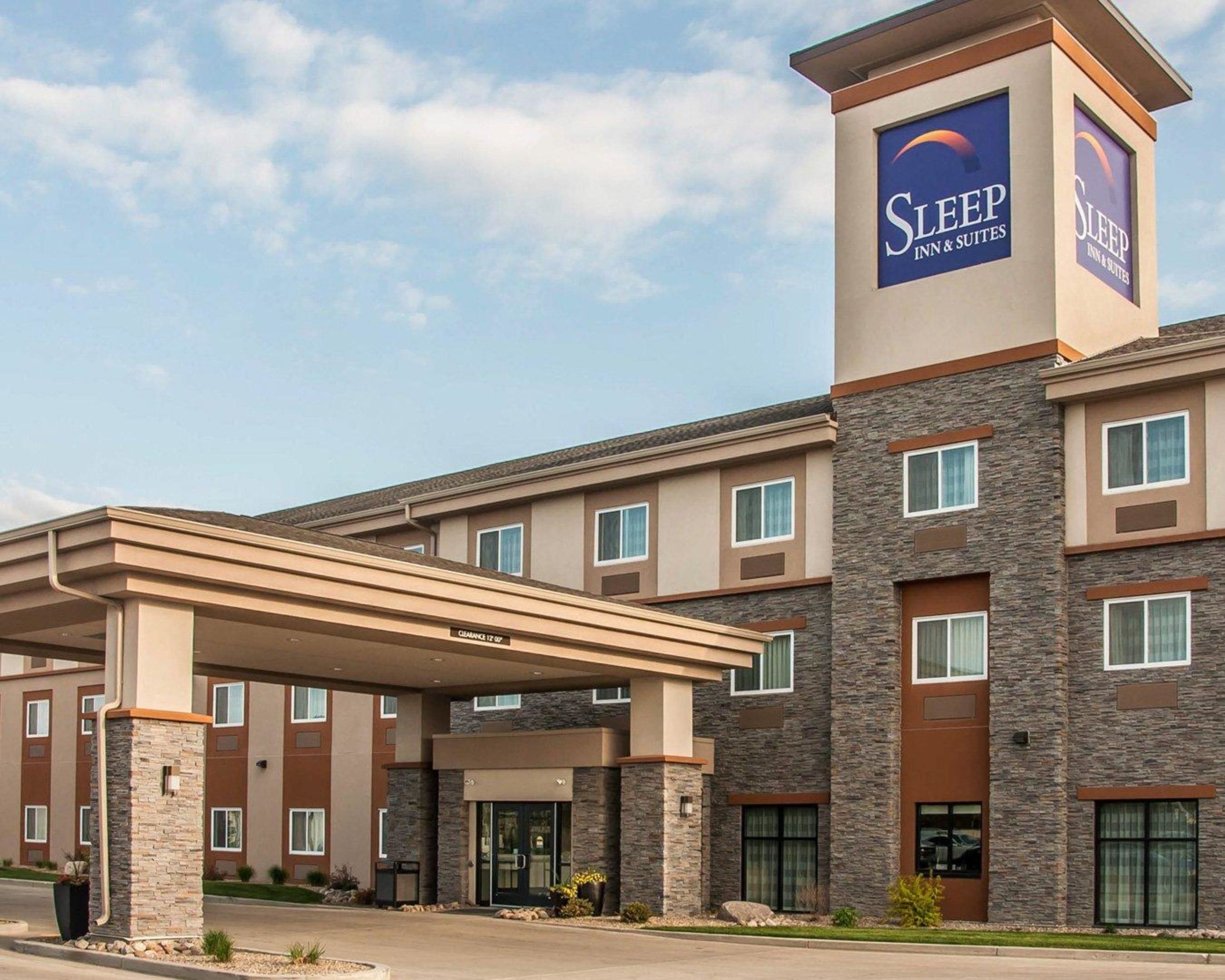 A Sleep Inn & Suites building with a covered entrance, stone facade, and multiple windows.