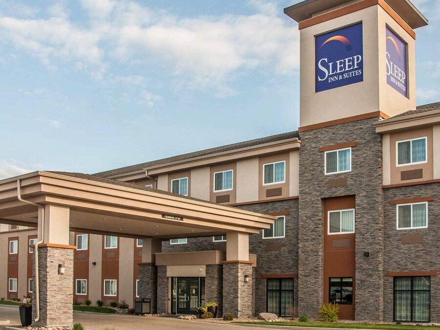 A Sleep Inn & Suites building with a covered entrance, stone facade, and multiple windows.