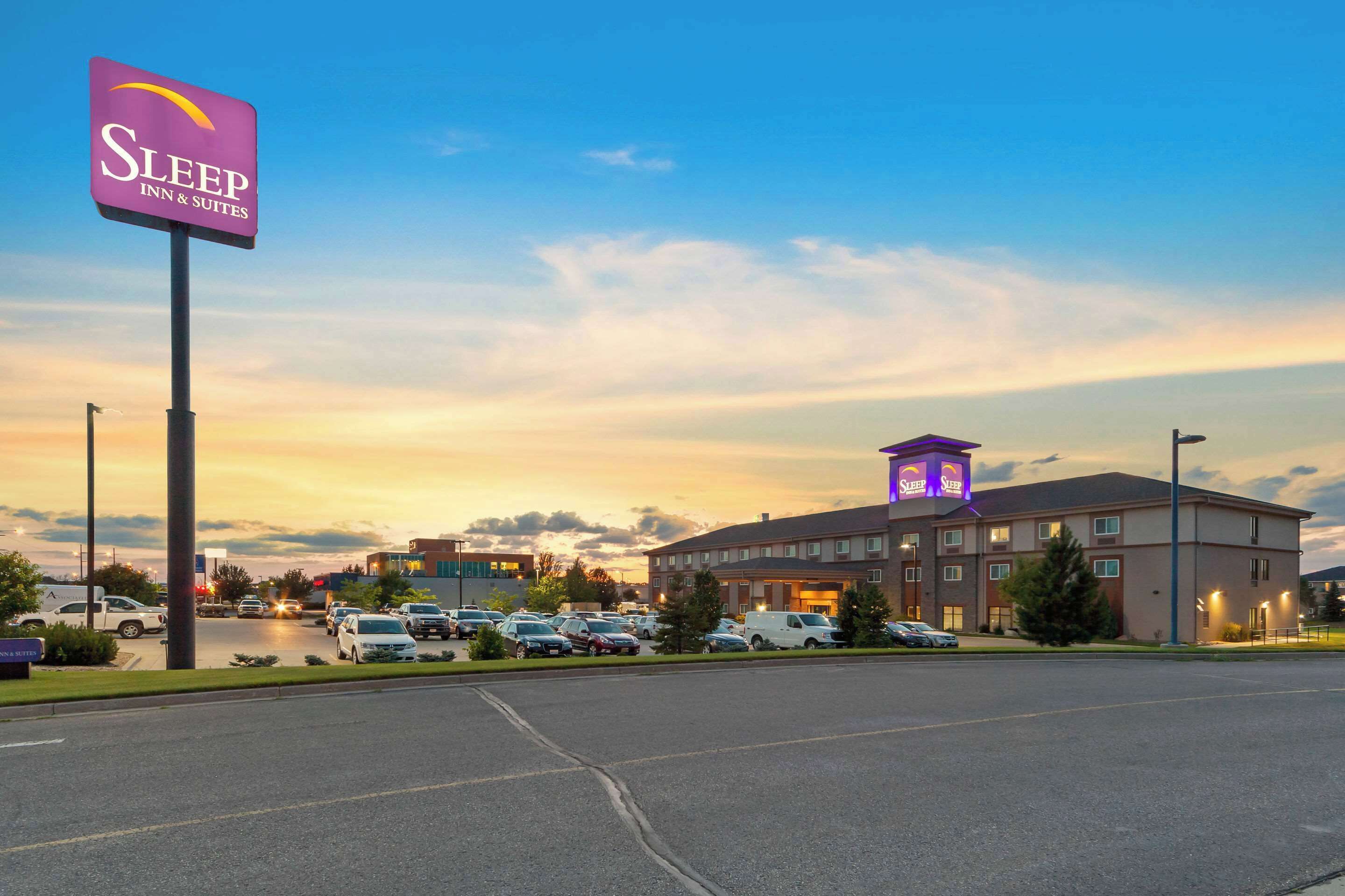A Sleep Inn & Suites hotel with a parking lot and a sunset sky.