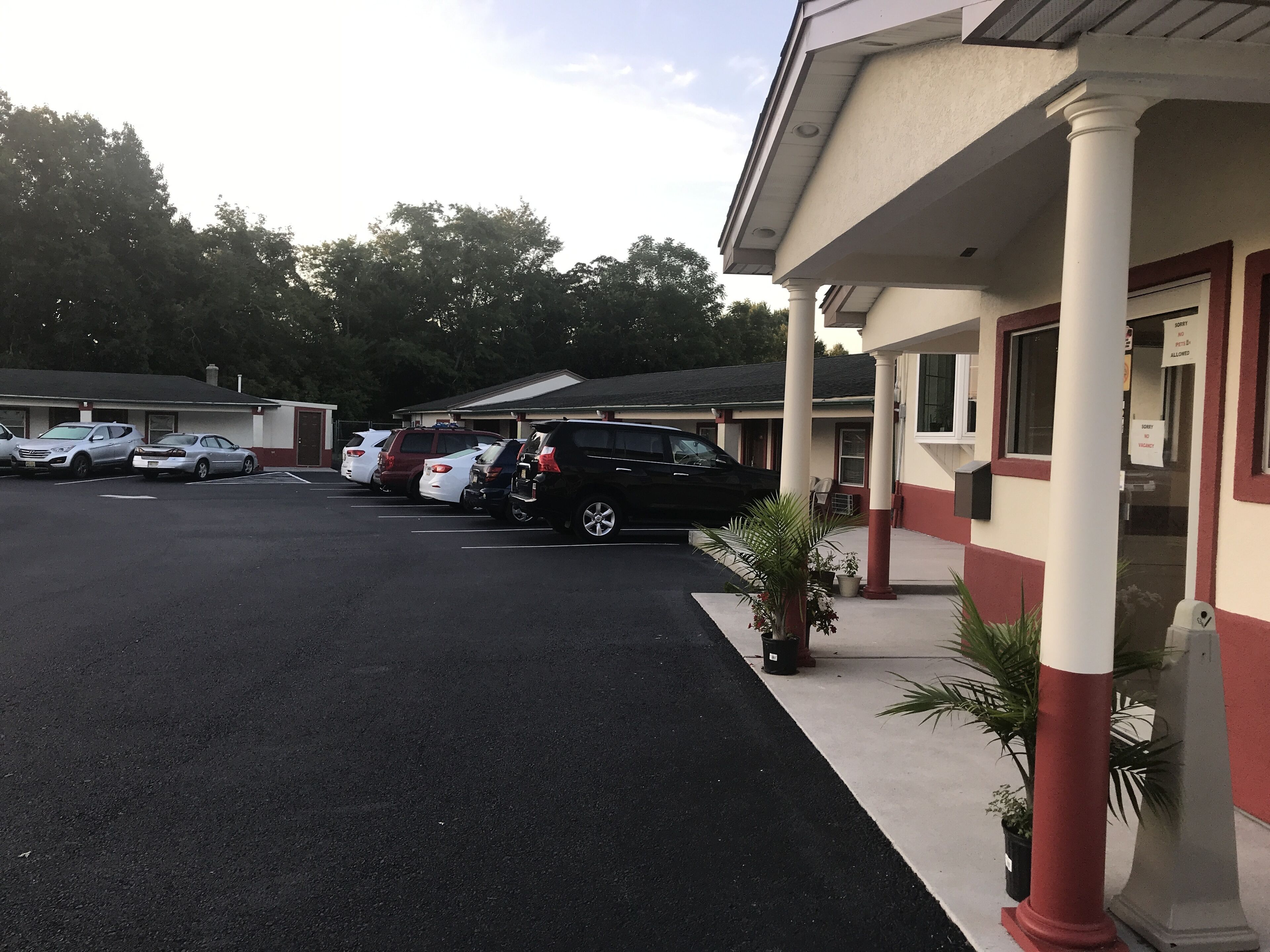 Un estacionamiento con varios coches aparcados frente a un edificio de fachada roja y blanca.