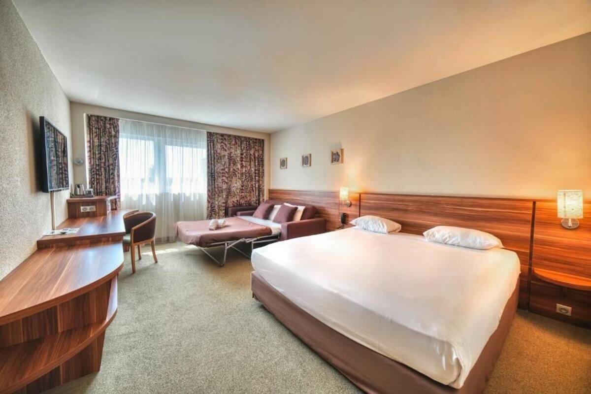 Une chambre d’hôtel avec un grand lit, un bureau, une chaise et un canapé.