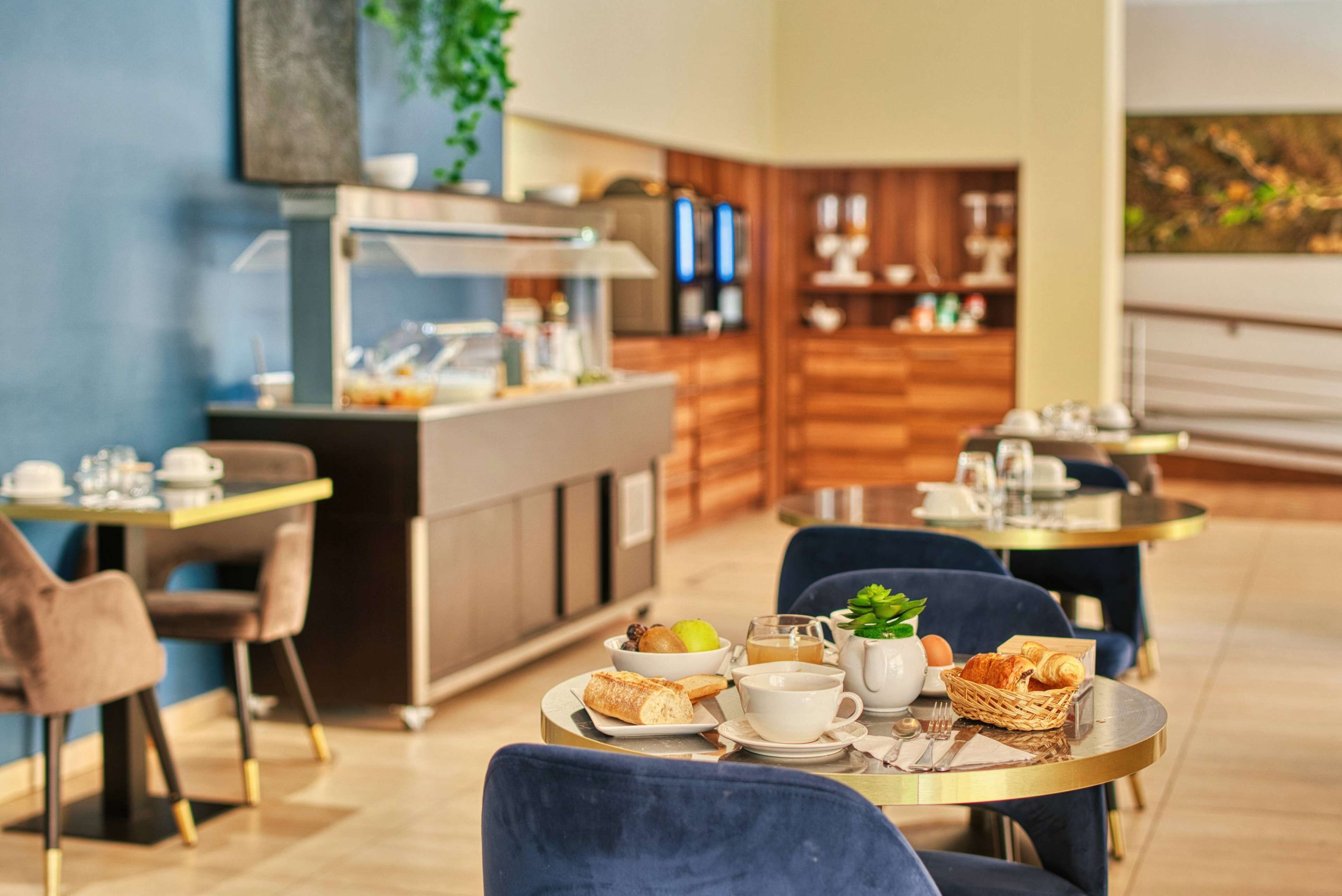 Un comedor con mesas y sillas, una barra de buffet y una cocina al fondo.