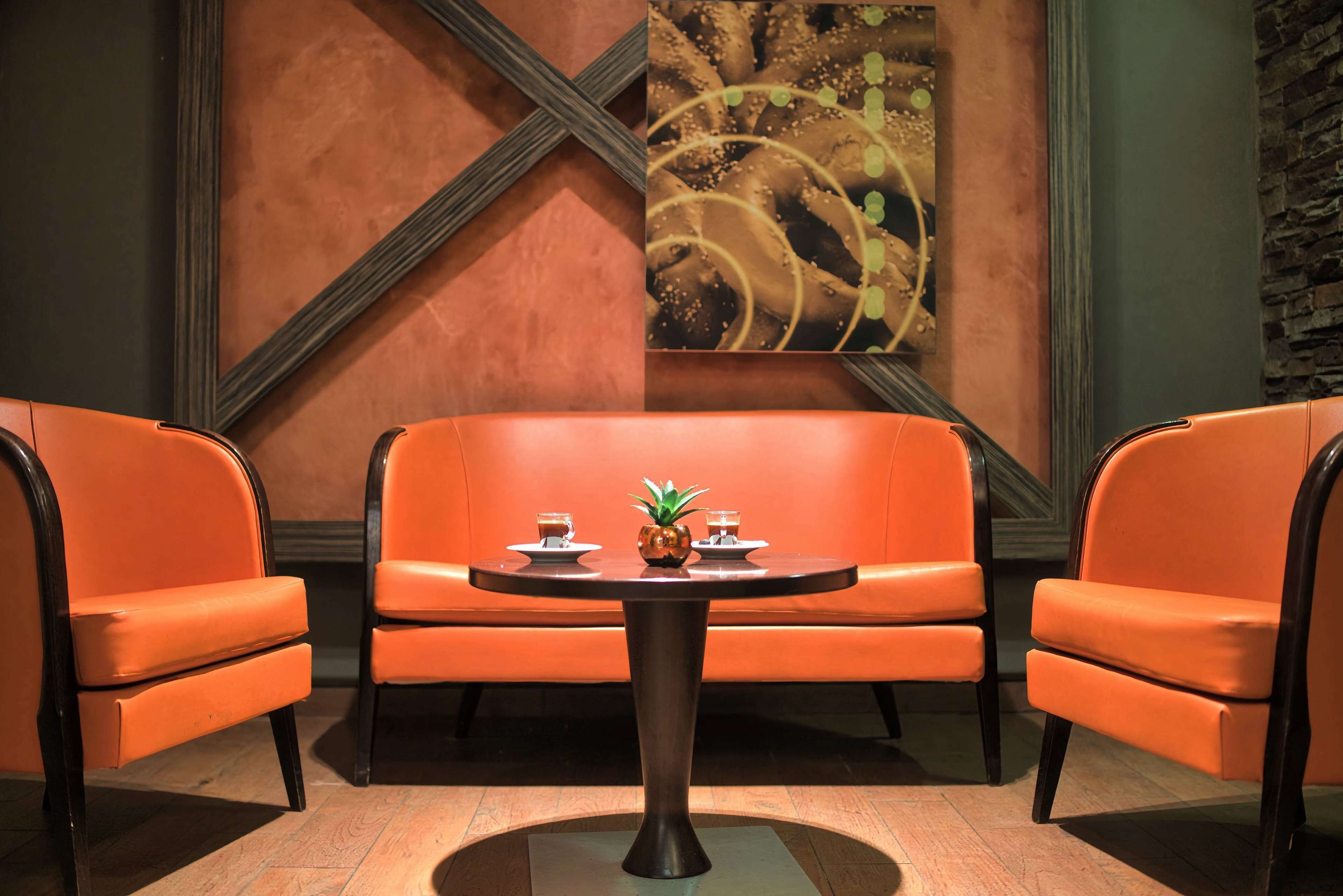 A room with a sofa, two chairs, a table, and a decorative wall piece.