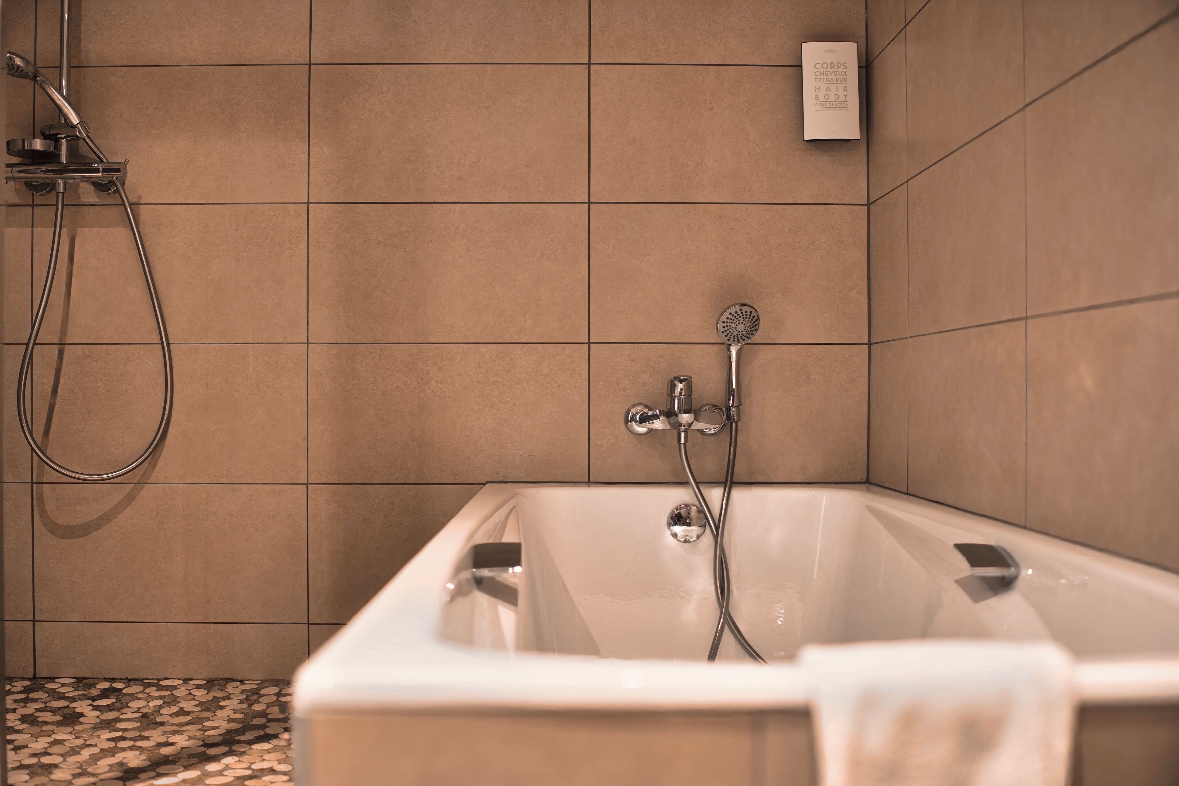 A modern bathroom with a bathtub, shower, and tiled walls.
