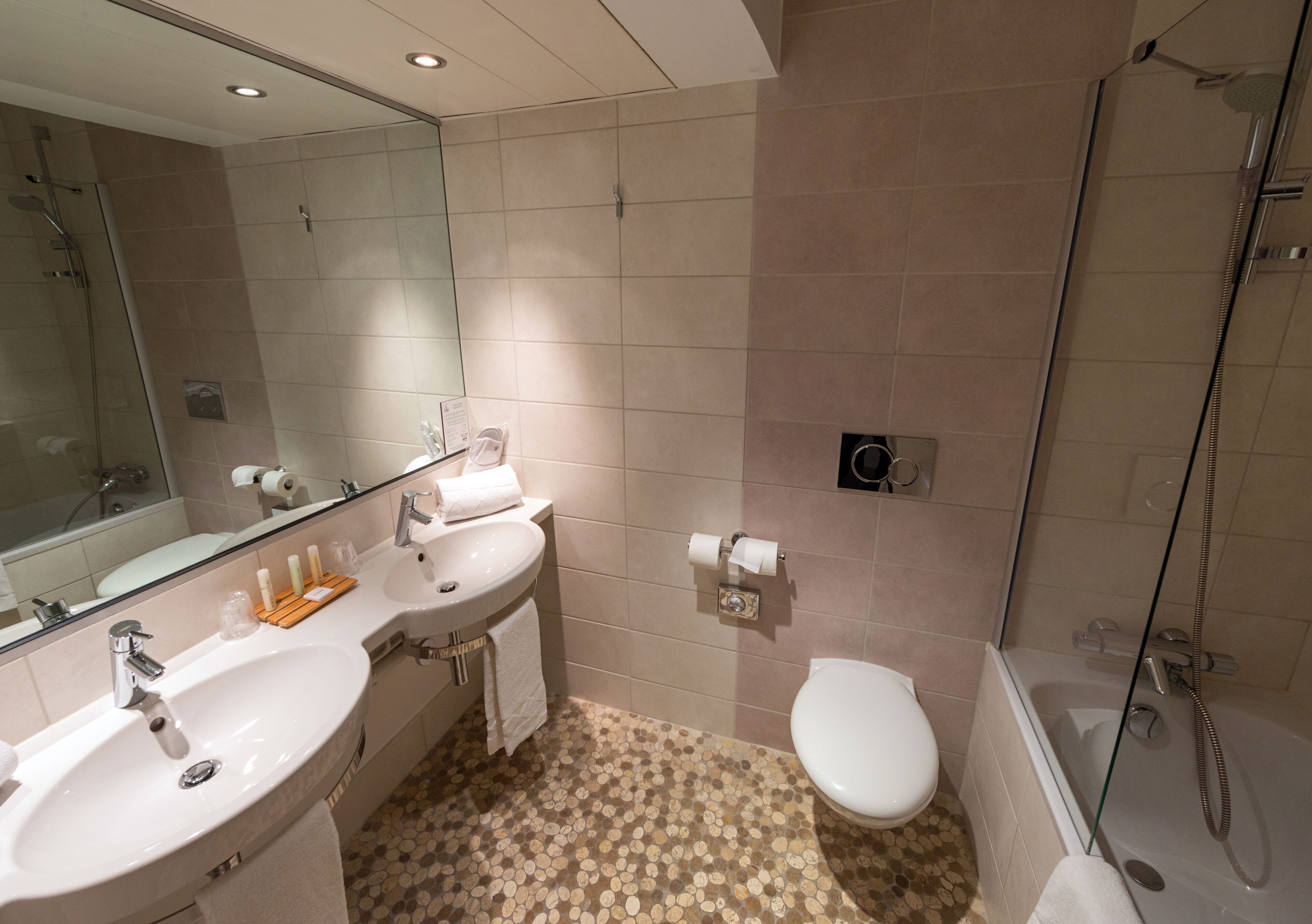 Une salle de bain moderne avec deux lavabos, des toilettes et une douche.
