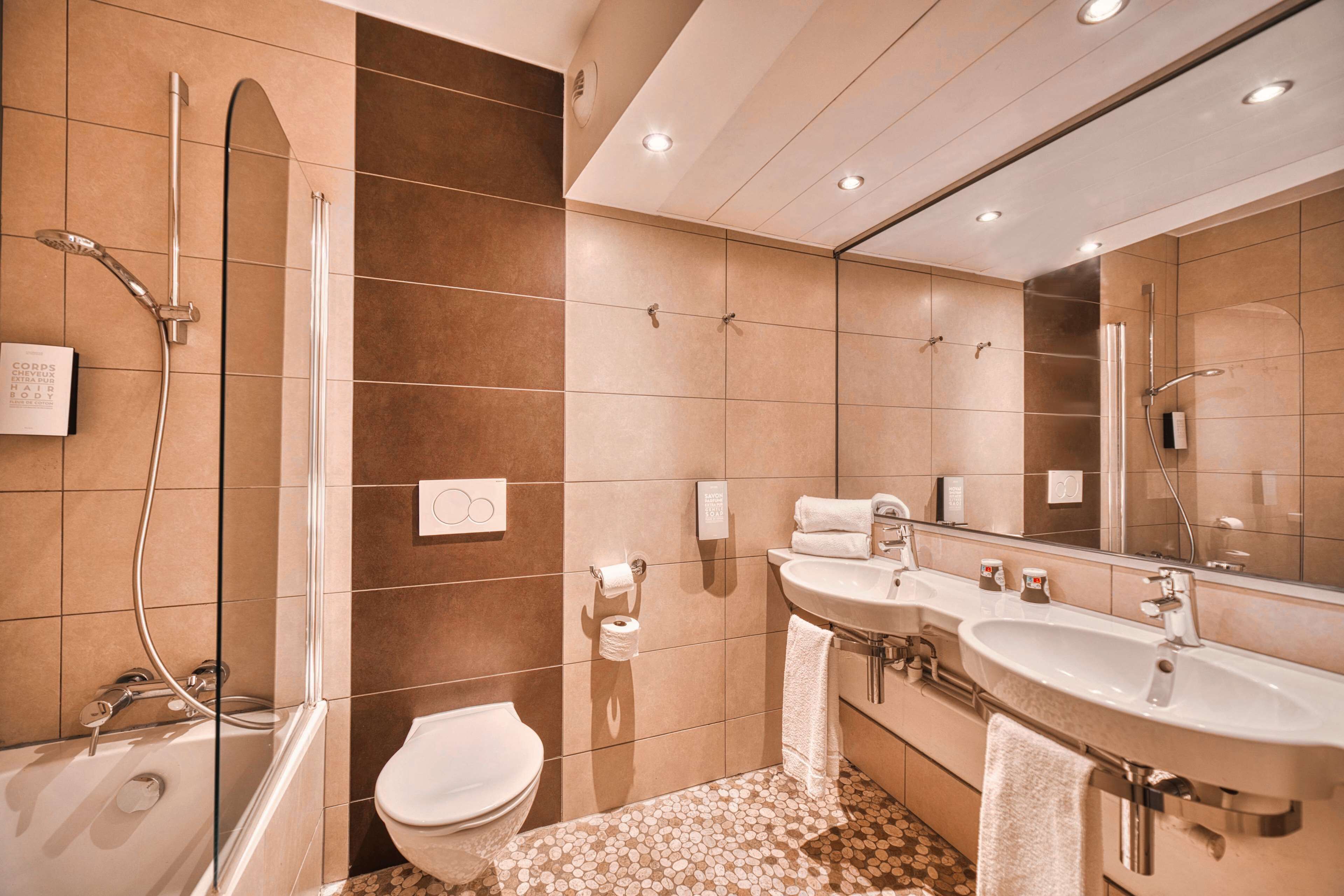Ein modernes Badezimmer mit Badewanne, Toilette und zwei Waschbecken.