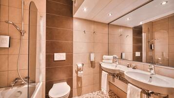 Ein modernes Badezimmer mit Badewanne, Toilette und zwei Waschbecken.
