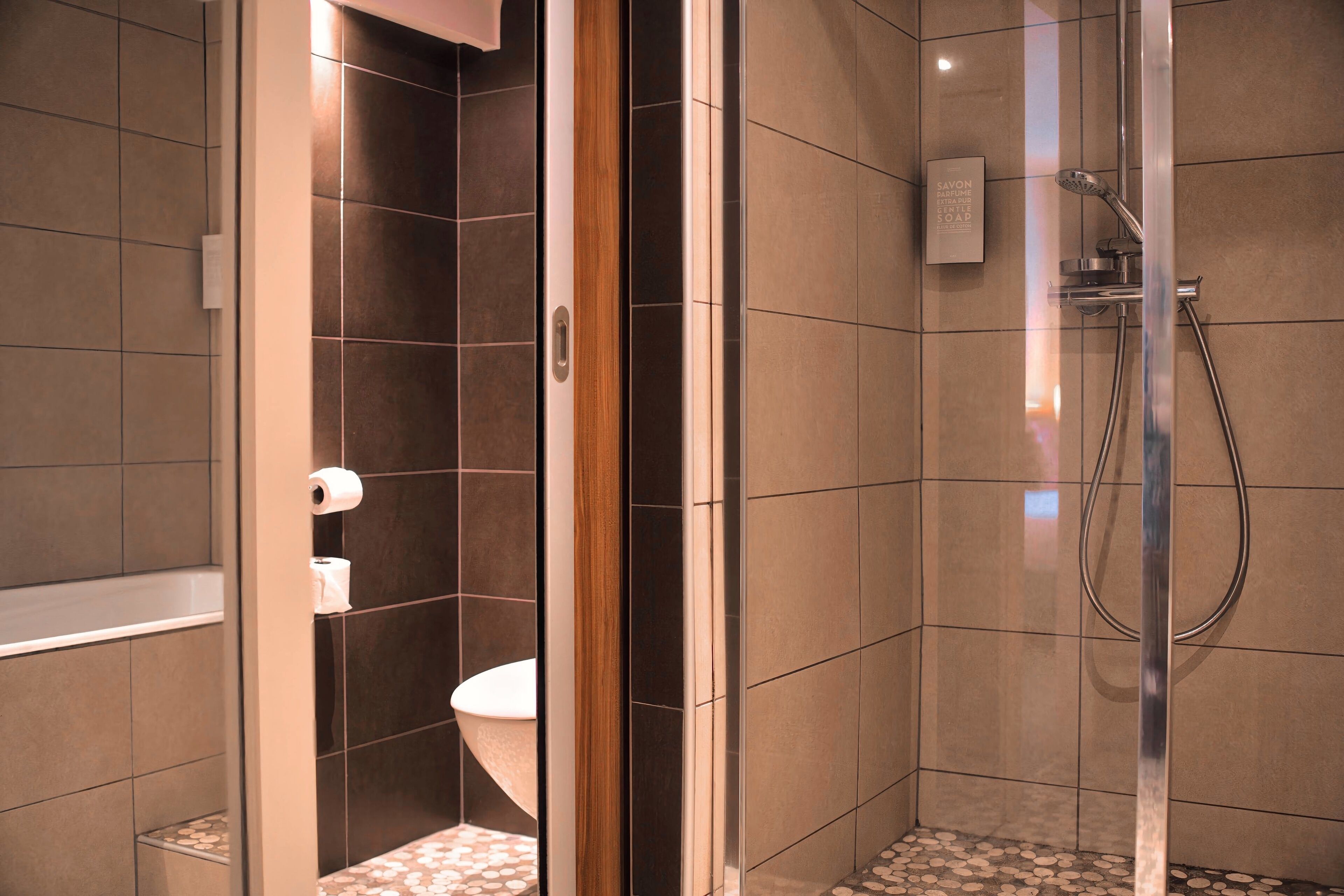 Un baño moderno con ducha de vidrio, inodoro y perchero para toallas.