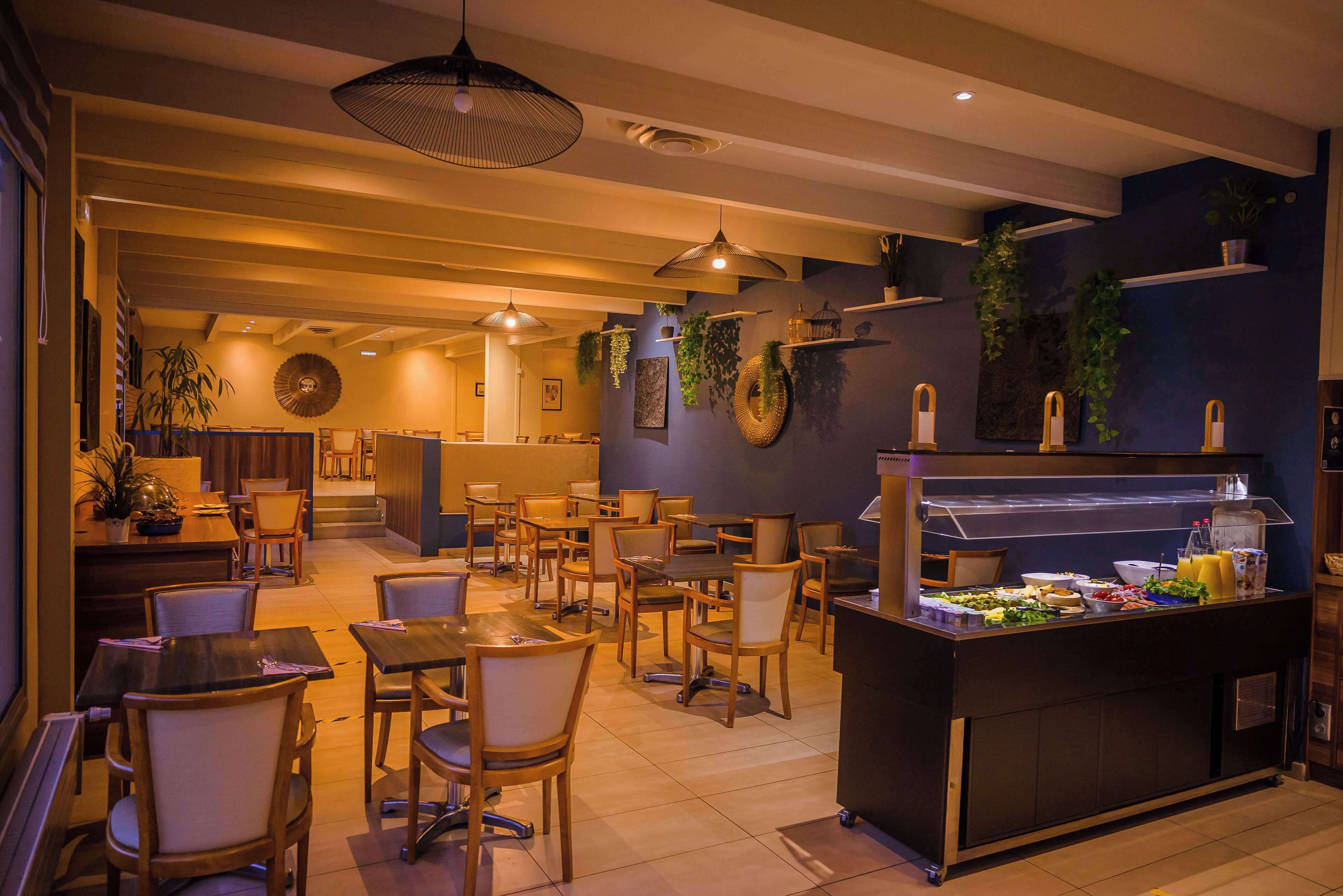 Een restaurant met verschillende eettafels en stoelen, een buffetbar met eten en planten aan de wanden.