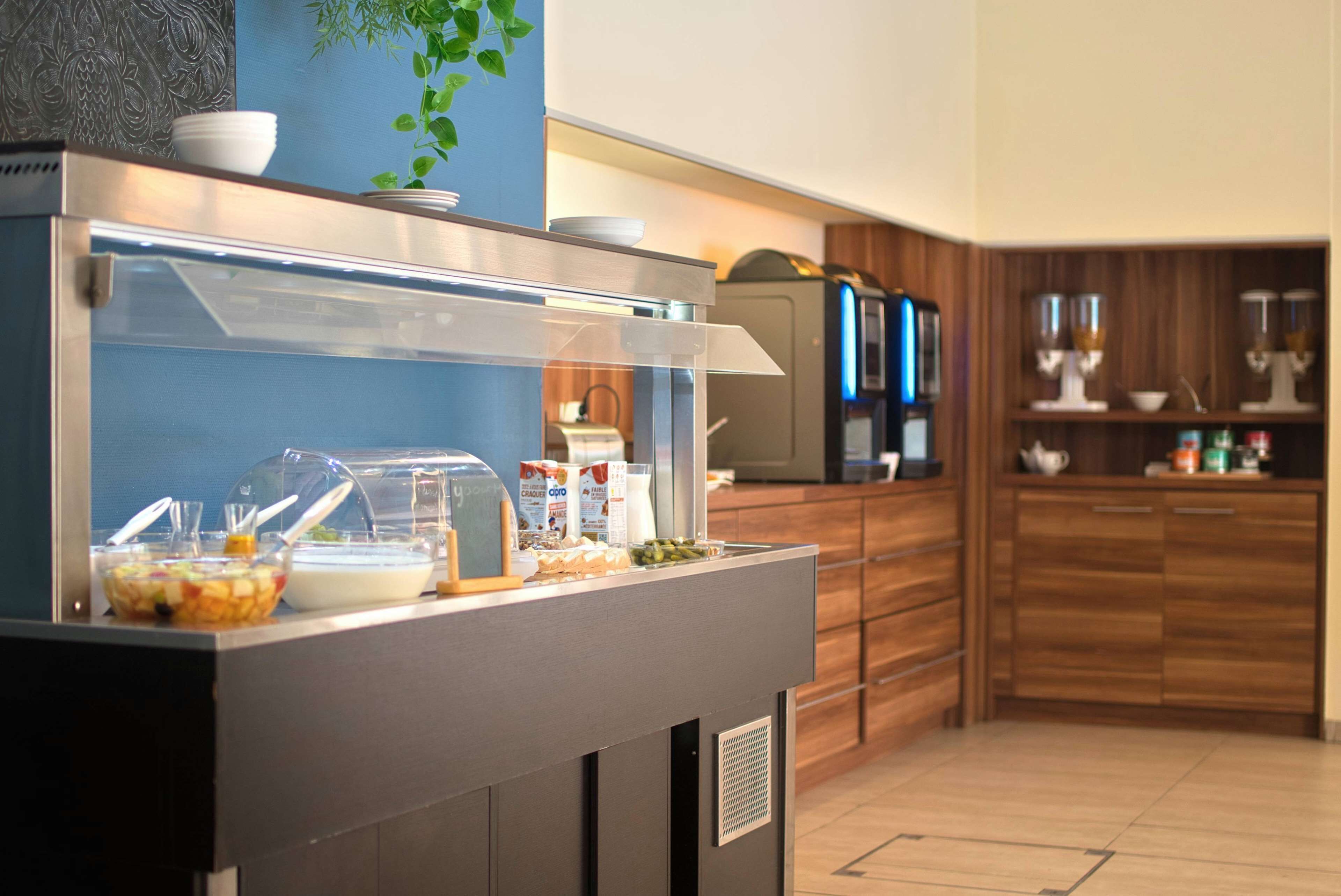 Zona de buffet con un recinto de vidrio, diversos alimentos y electrodomésticos de cocina al fondo.