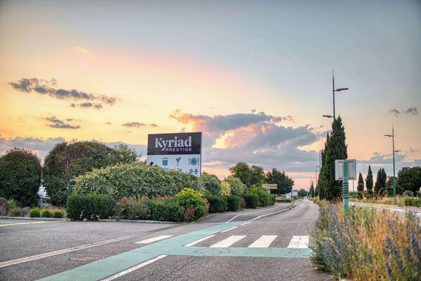Una carretera con un cartel que indica 'Kyriad Prestige' y un paso de peatones.
