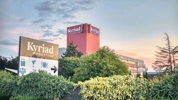 Et hotelskilt med teksten 'Kyriad Prestige' og pile, der angiver vej.