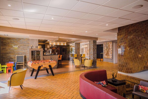 A lobby with a foosball table, seating area, and a bar. - KYRIAD PRESTIGE MULHOUSE - Basel (Sausheim)
