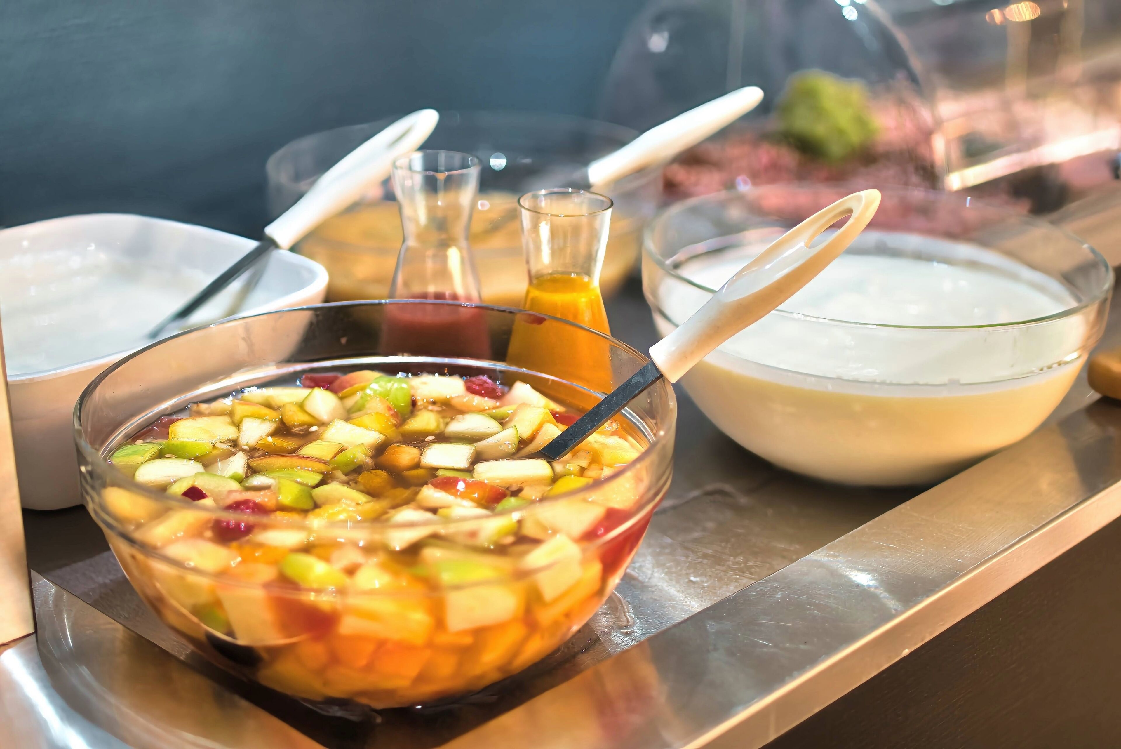 Forskellige spisemuligheder på et fad, herunder en skål frugtsalat, en skål suppe og et glas juice.