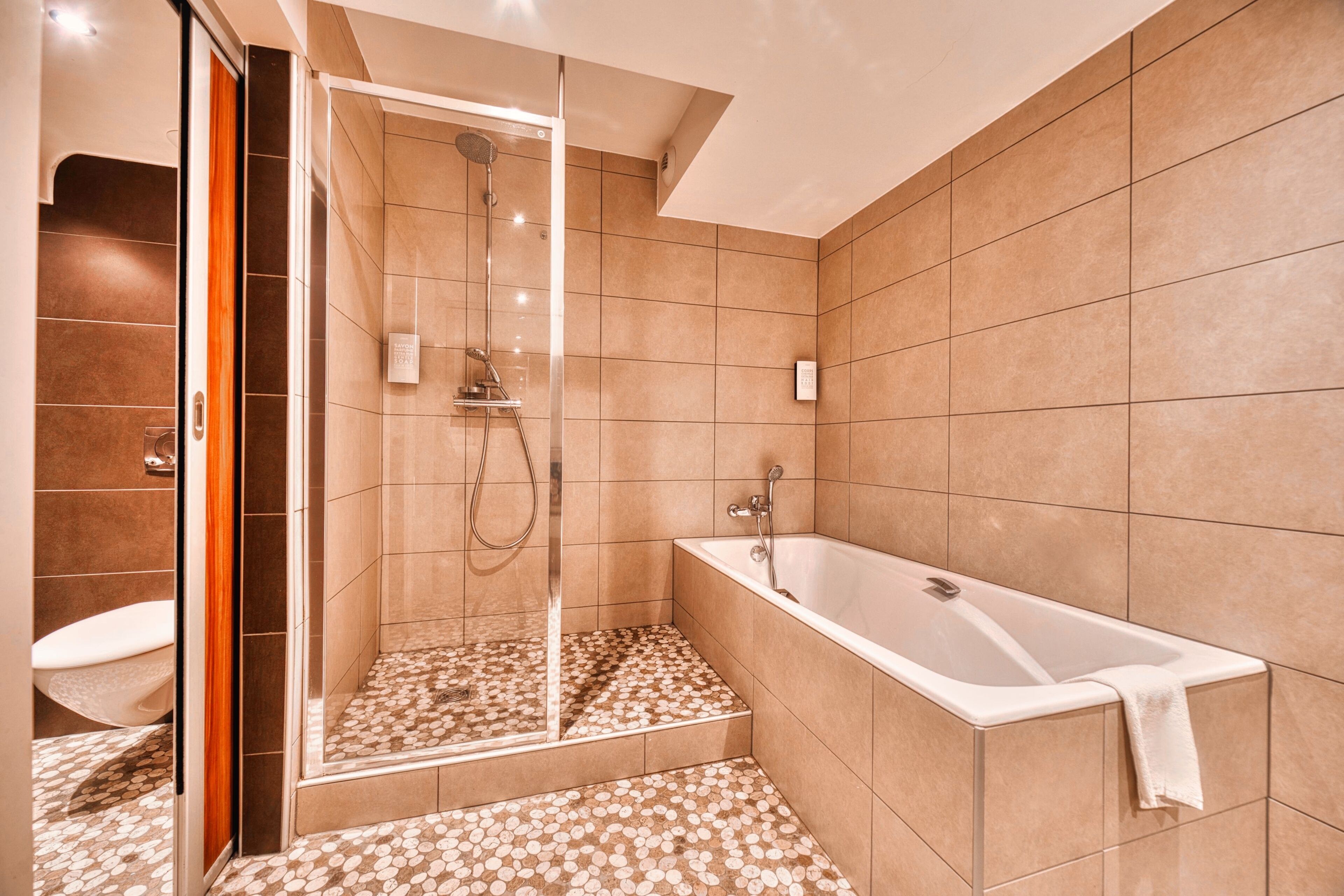 Une salle de bain moderne avec une douche à l’italienne, une baignoire et des toilettes.