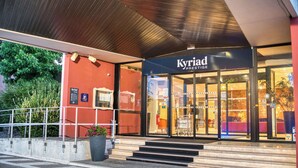 The exterior of a hotel named 'Kyriad Prestige' with a modern design, featuring a red facade, glass entrance, and a staircase leading to the entrance. - KYRIAD PRESTIGE MULHOUSE - Basel (Sausheim)