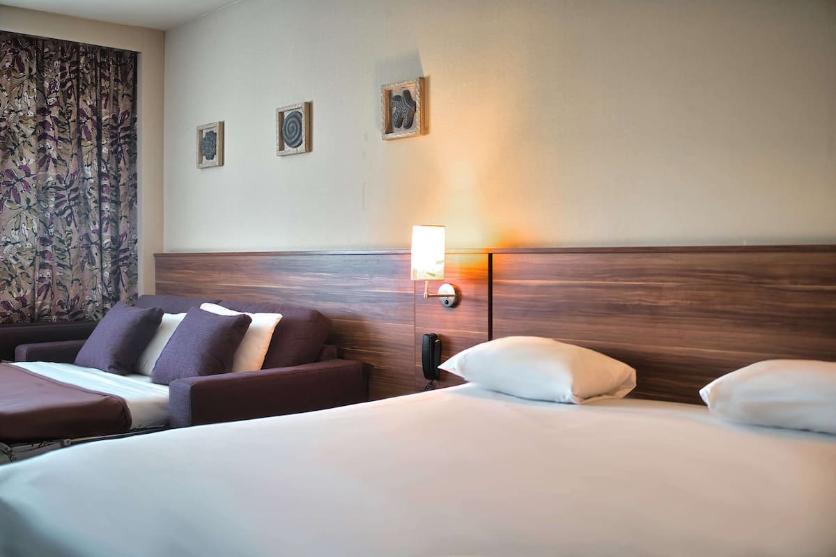 Une chambre d’hôtel équipée d’un lit, d’un canapé, d’un bureau et d’un téléphone.