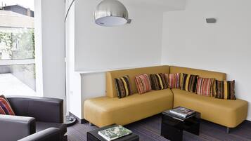 A modern living room with a yellow sectional sofa, striped pillows, a black coffee table, and a floor lamp.