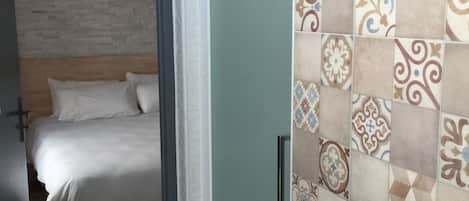 A bedroom with a bed, a bathroom with a sink, and a shower area.