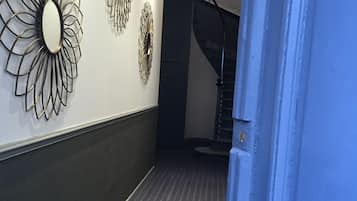 Ein Flur mit Teppichmuster, einer blauen Tür und Wanddekoration.