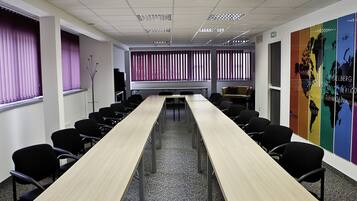A conference room with a long table, black chairs, and a world map on the wall.