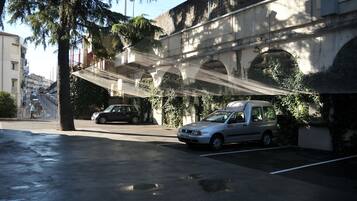 A parking area with a car and a building with a covered walkway.