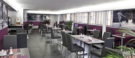 Un restaurante moderno con una distribución limpia, que cuenta con varias mesas y sillas, ventanas grandes con persianas y un mural en la pared.