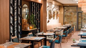 A restaurant with multiple dining tables and chairs, a wall-mounted wine rack, and a large mirror. - Arche Hotel Puławska Residence (Warsaw)