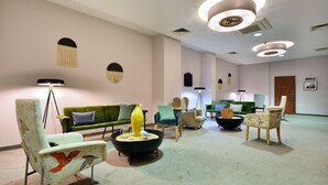 A modern lounge area with a green sofa, a yellow vase, and a black coffee table. - Arche Hotel Puławska Residence (Warsaw)