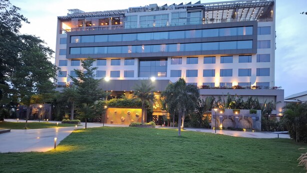 A modern multi-story hotel with a glass facade, outdoor lighting, and landscaped gardens. - Daspalla Hyderabad (Hyderabad)